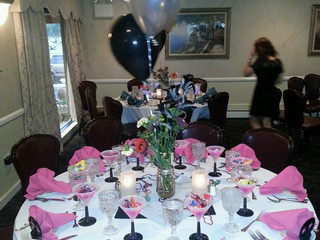 Sweet 16 birthday party setup, round table with white table cloth, black and pink napkins, black party masks, center pieces created with a mason jar f
